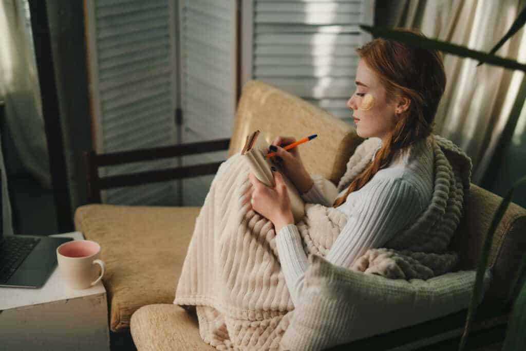 Cute lady with eyes patches at home writing notes on a diary while relaxing taking a break, enjoying home lifestyle. Resting, vacation, beauty treatment, meditation, calmness, harmony concept